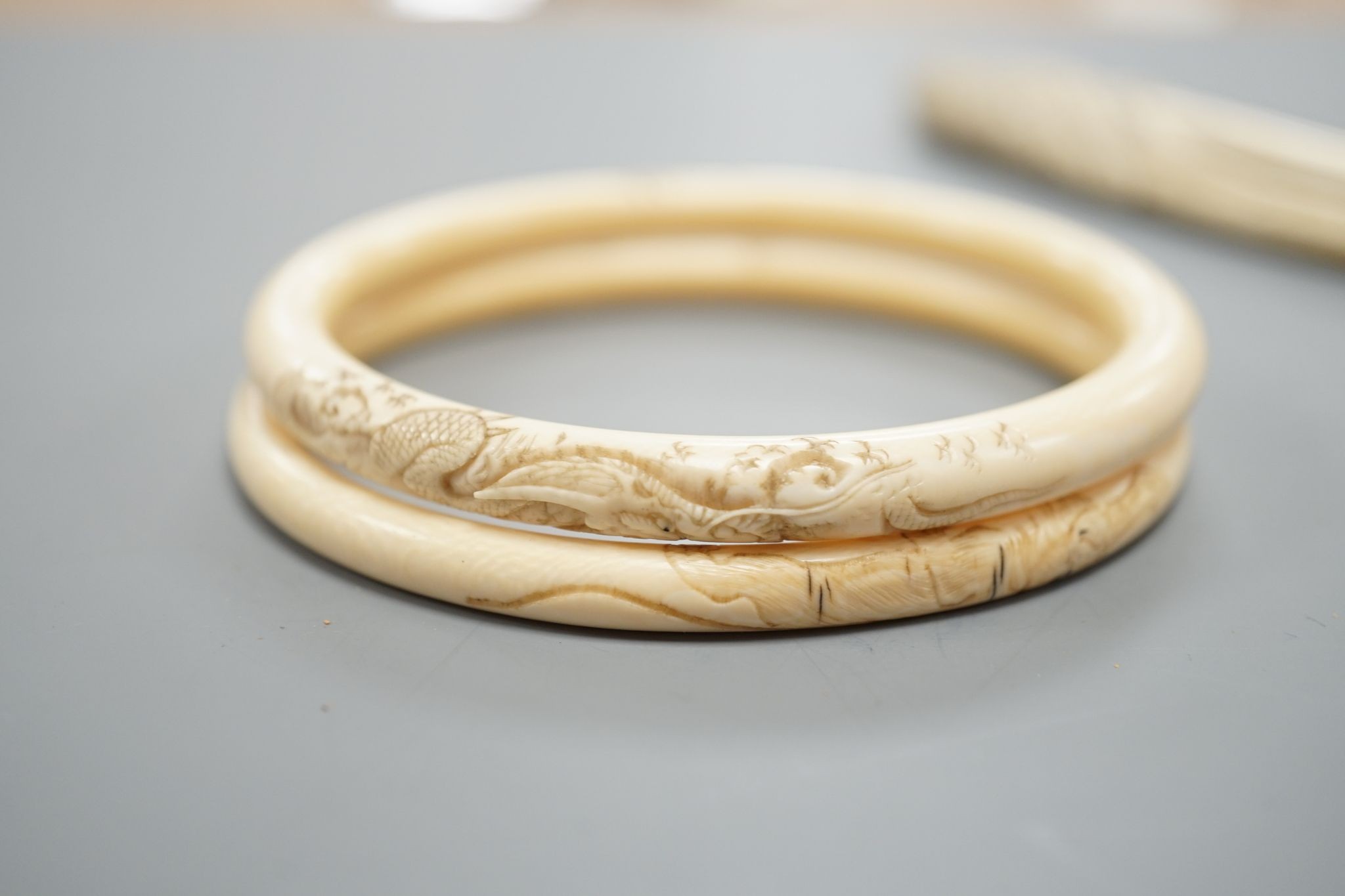 A late 19th century carved ivory ‘parrot’ paper knife and two Japanese carved Ivory bangles, paper knife 22 cms long.